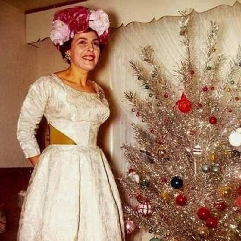 Pictured here is a similar dress from this 1960s collection, styled for a festive holiday look by an aluminum Christmas tree. Your dress features the same charming champagne jacquard fabric, knee-length skirt, and bronze satin waist insets, offering a timeless vintage vibe perfect for winter weddings or holiday parties. Please see actual images for the exact condition and details of your dress.