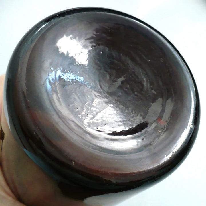 19th-century hand-blown amber glass apothecary jar with a label indicating it once contained cardamon seed powder. The jar has a dark amber color, a narrow neck, and a round stopper. Bottom.