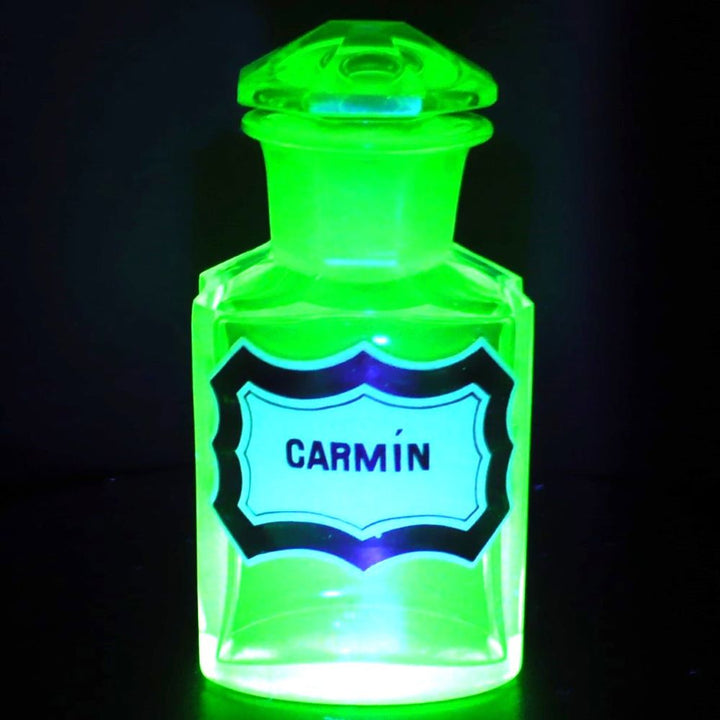 Uranium glass apothecary bottle glowing under uv light.