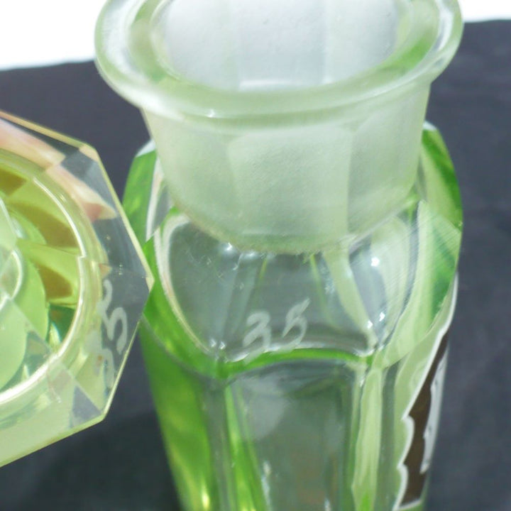 Uranium glass apothecary bottle under regular light showing matching etched numbers.