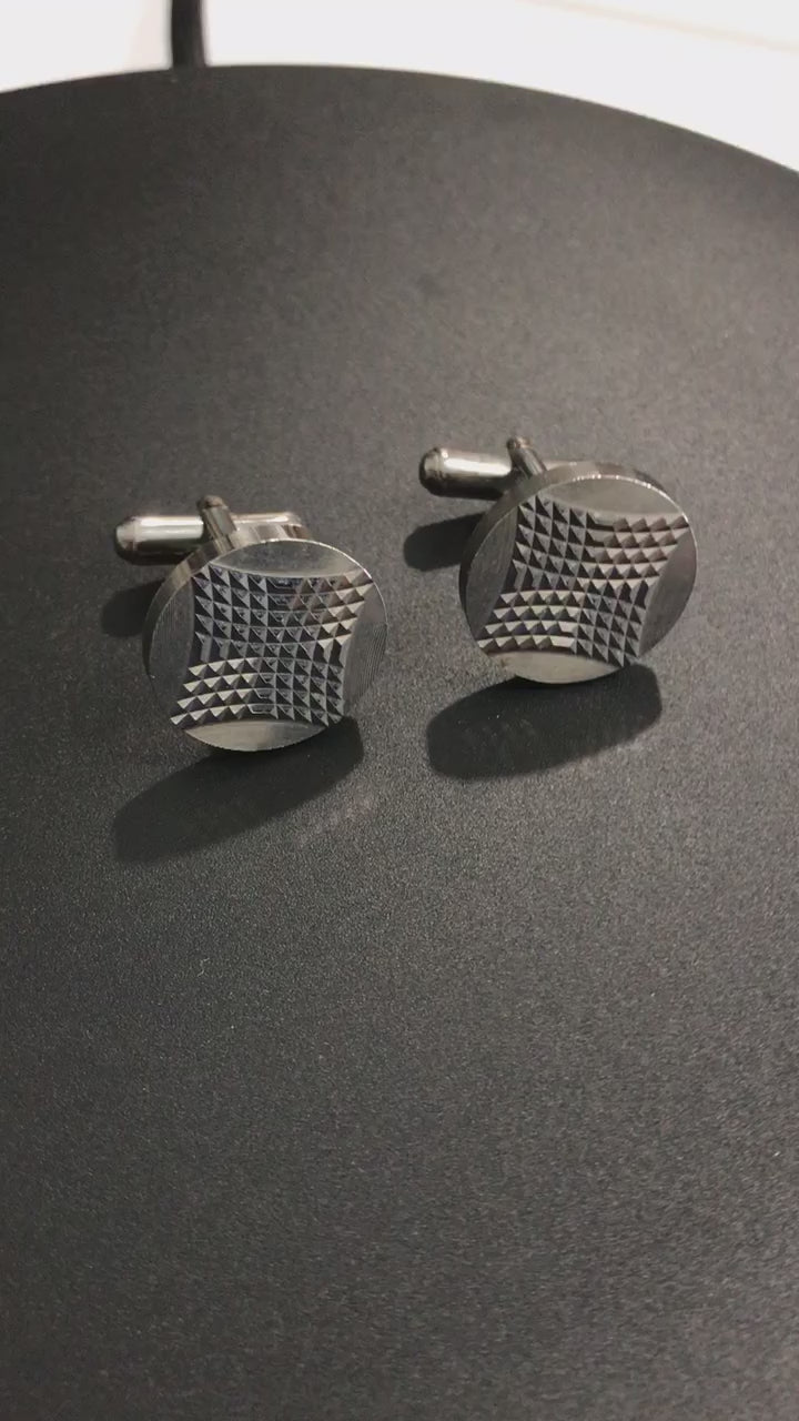 video of the cufflinks being turedon a display to show the light reflecting off the angled small facets that make up the design on the face o f the cufflink.