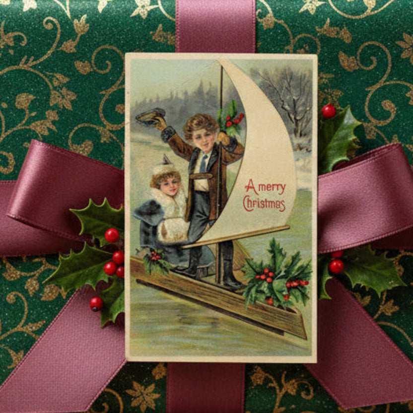 1907 Children Sailing Into Christmas On An Iceboat Vintage Postcard, shown used as a gift topper.