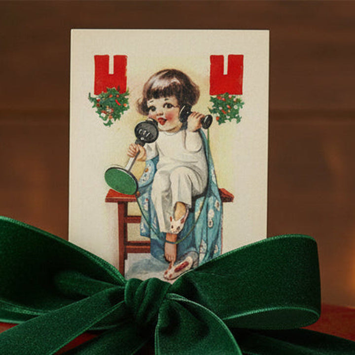 1910s A Christmas Call in Bunny Slippers WW1 Vintage Holiday Postcard, shown used as a gift topper.