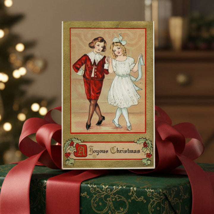 1915 A Christmas Country Dance Gilded Embossed Vintage Postcard on a wrapped gift with a blurred Christmas tree in the background