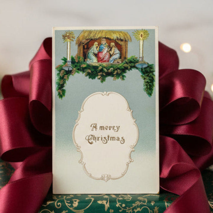 Decorative Christmas gift with green paper, red ribbon, and v1911 Gilded Mantel Nativity Scene Vintage Christmas Postcard gift topper.