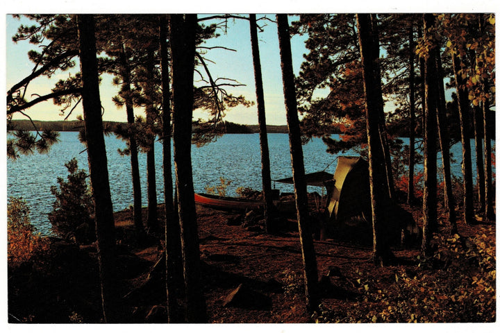 Camping scene with a tent and canoe by a lake surrounded by trees
