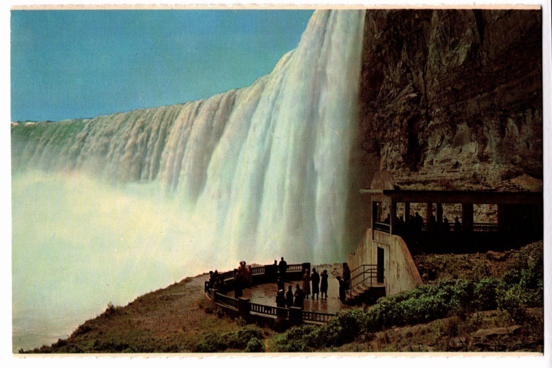 Niagara Falls with a viewing platform and people observing the waterfall vintage postcard.