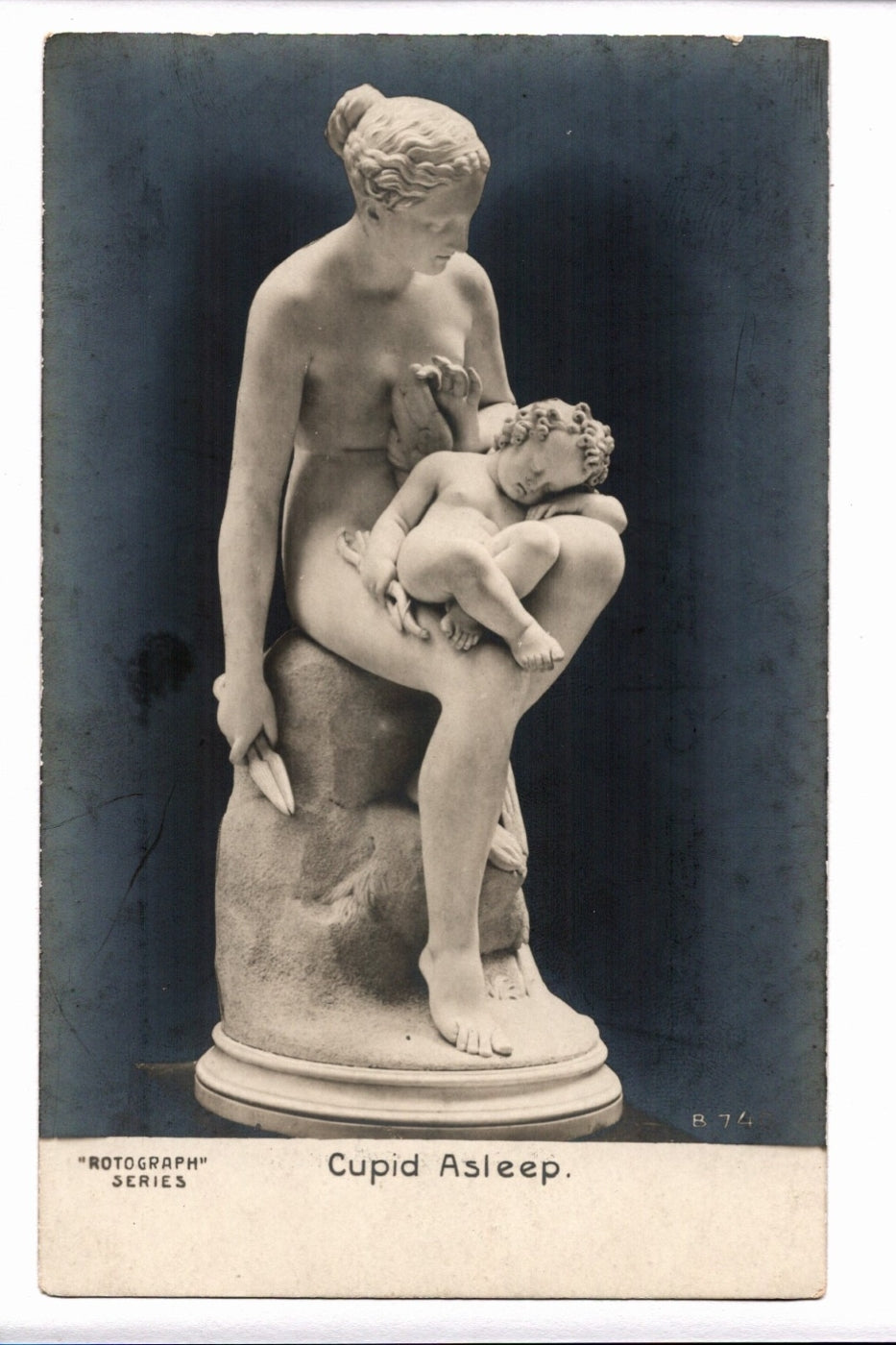Statue of a woman holding a child labeled 'Cupid Asleep' on a dark background