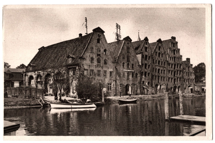 Historical black and white photo of warehouses along a canal with boats. Salt Storehouses Salzspeicher Lübeck Germany.