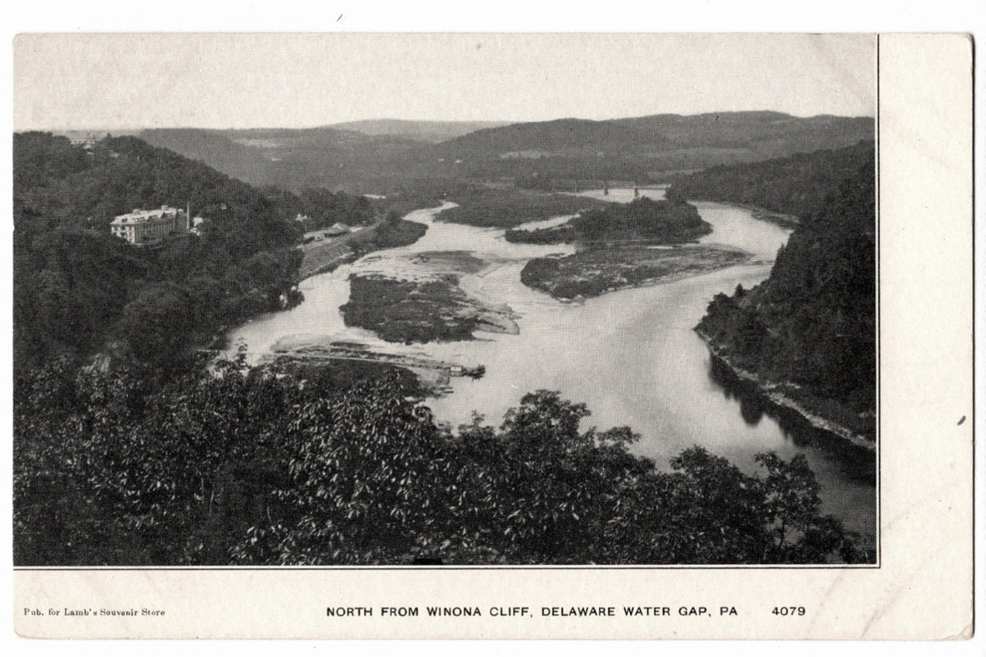 an expansive northward view of the Delaware River from Winona Cliff at the Delaware Water Gap in Pennsylvania. The image shows the river winding through the gap with several small islands visible in the stream. On the left hillside, the Kittatinny House resort hotel is perched overlooking the valley.