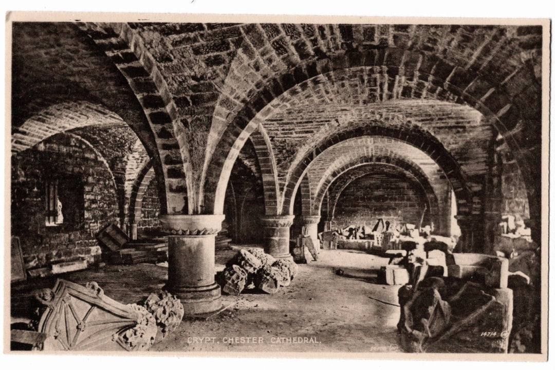 The image showcases the heavy Norman (Romanesque) vaulted ceilings and stout stone pillars that date back to the cathedral's origin as a Benedictine abbey. The floor is strewn with various carved stone fragments and architectural relics, likely stored there during restoration efforts..