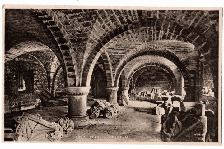 The image showcases the heavy Norman (Romanesque) vaulted ceilings and stout stone pillars that date back to the cathedral's origin as a Benedictine abbey. The floor is strewn with various carved stone fragments and architectural relics, likely stored there during restoration efforts..