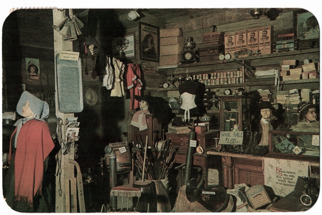Vintage interior of a store with mannequins, clothing, and shelves filled with goods. 1961 Pikes Peak Ghost Town General Store Colorado Springs Vintage Postcard.