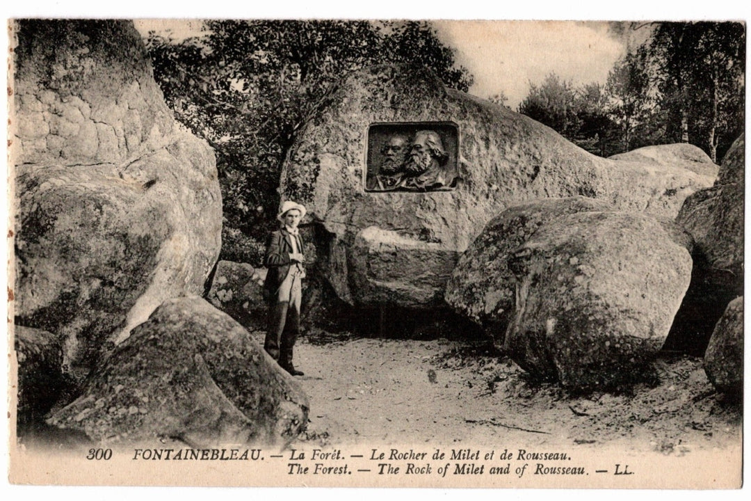 Vintage postcard of a person standing next to large rocks with a carved face, labeled 'La Forèt' and 'The Rock of Milet and de Rousseau'.