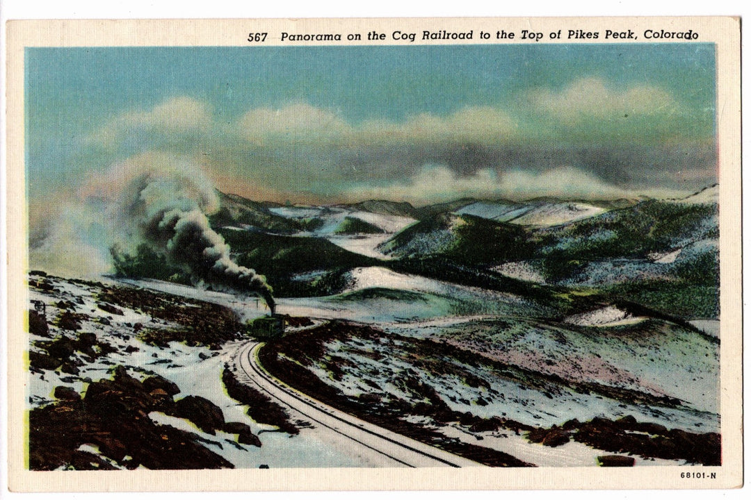 Vintage postcard of a scenic view with a train on a mountain road, labeled 'Panorama on the Cog Railroad to the Top of Pikes Peak, Colorado'.