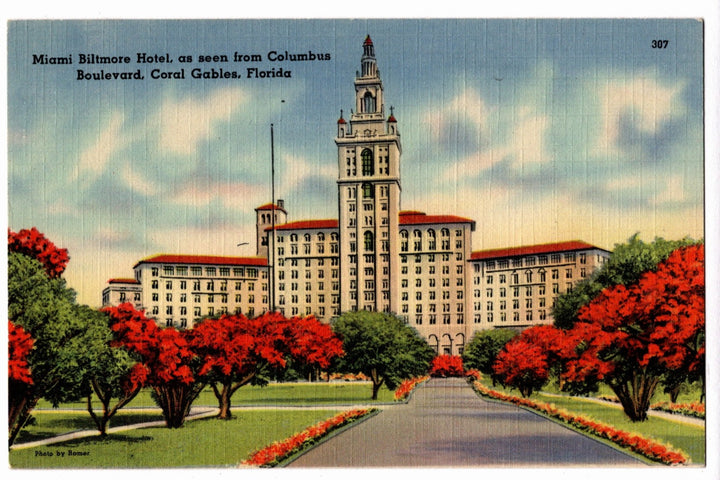 Vintage postcard of the Miami Biltmore Hotel with a pathway and red trees.