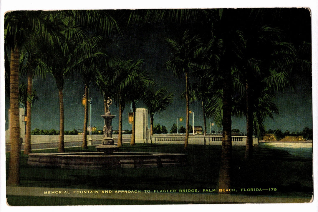 Memorial fountain and approach to Flagler Bridge in Palm Beach, Florida, with palm trees at night.