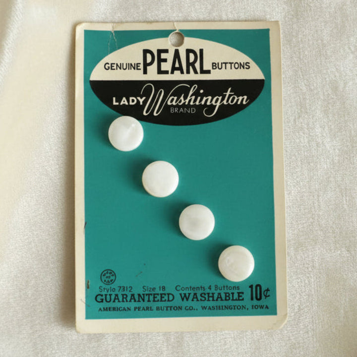 A set of four white, round pearl shank buttons on a teal-colored card with the text 'Genuine PEARL Buttons Lady Washington' and other details.