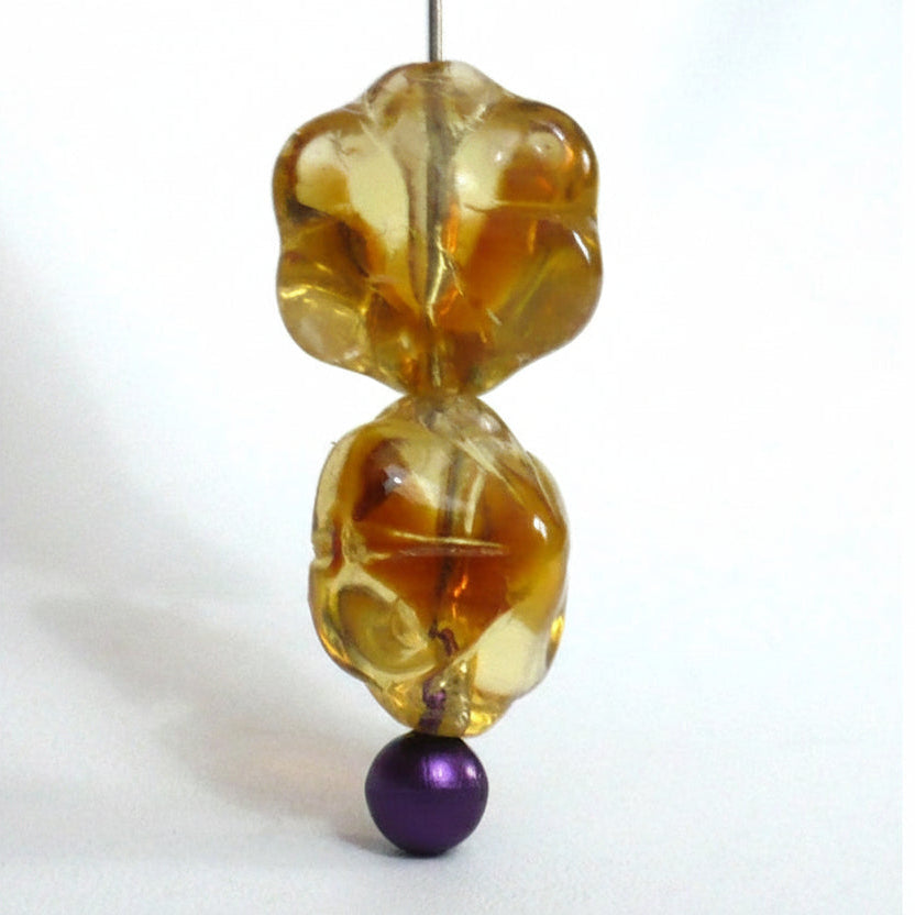  1910s Vintage 8x11 mm Czech Topaz Glass Beads shown strung through a sewing stick pin, angle view 2)
