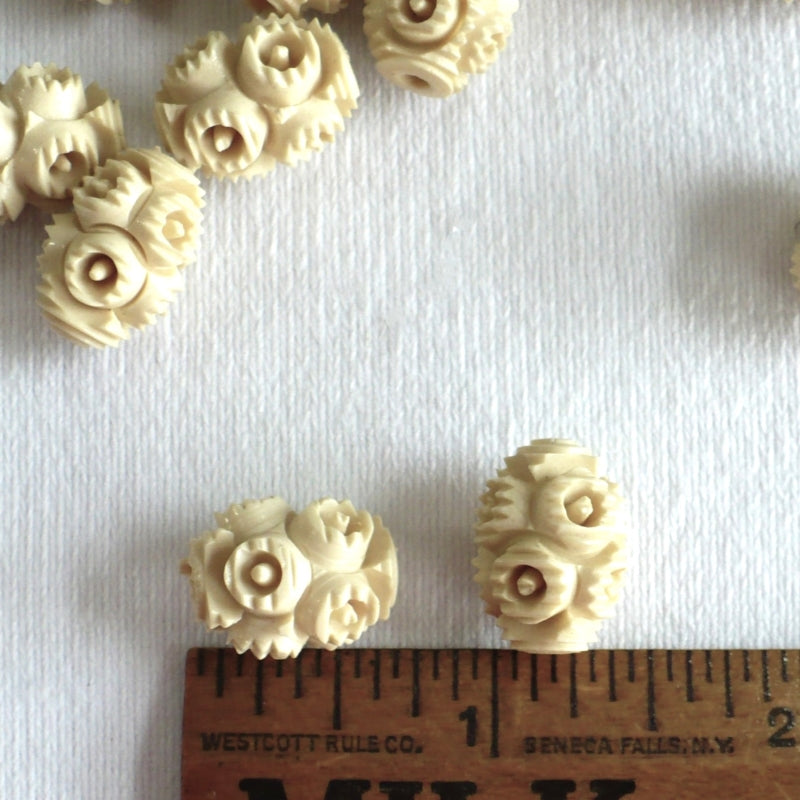 1930s French Ivory Celluloid Beads on a white velvet background, close-up next to a wood ruler for scale.