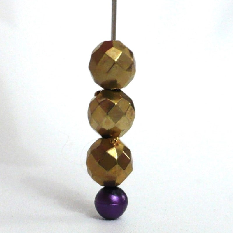 Three 1910s Round Faceted Brass Beads strung on a sewing stick pin.
