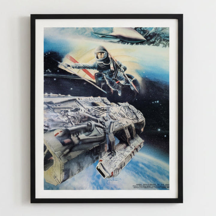 Framed artwork of a space scene with a spaceship and astronaut, on a white wall.