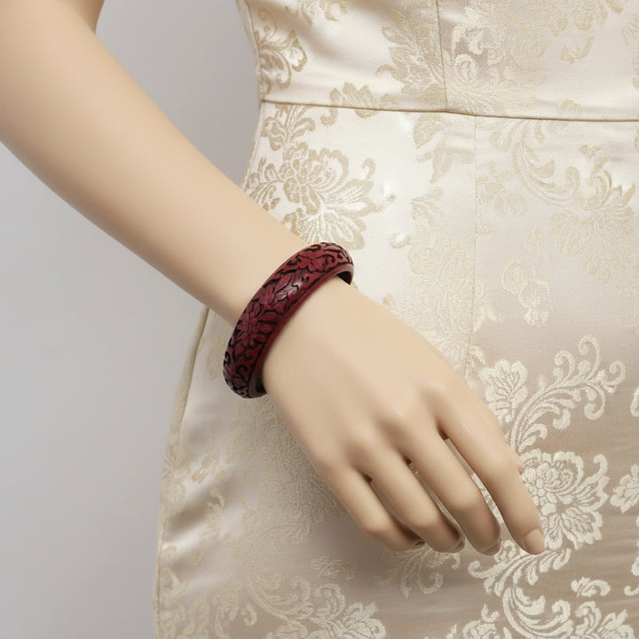 Vintage Auspicious Carved Red Cinnabar Bangle Bracelet worn by lady in dress.