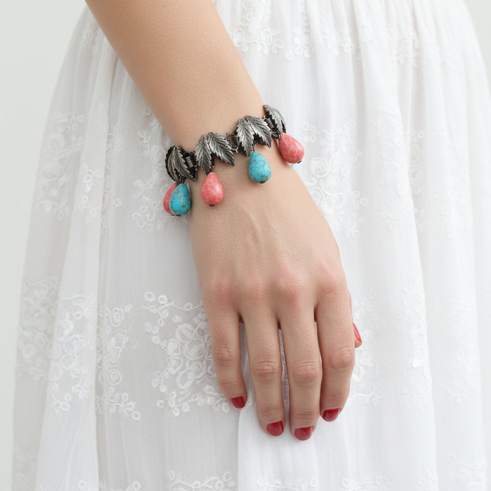 1930s Charm Bracelet with Hubbell Glass Beads, Native American-Inspired, on wrist of woman wearing white dress