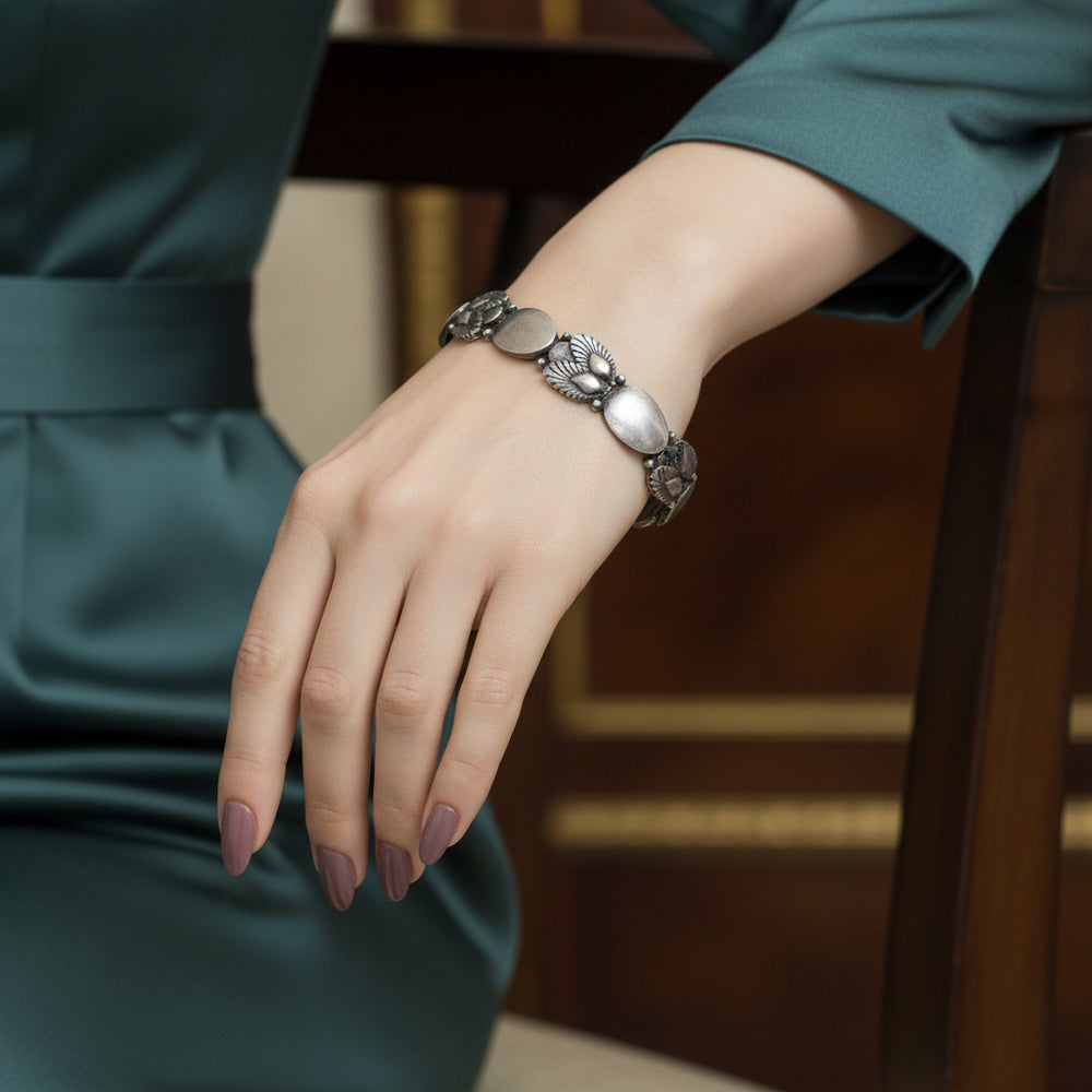 1945 Georg Jensen Pinje Bracelet on lady wearing green dress.