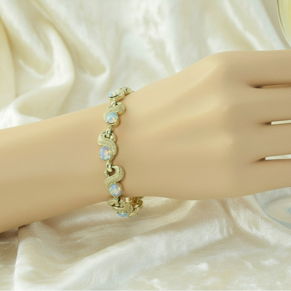 1950s Mid Century Vintage Aurora Borealis Crystal Bracelet worn on a wrist, shown on cream velvet background,