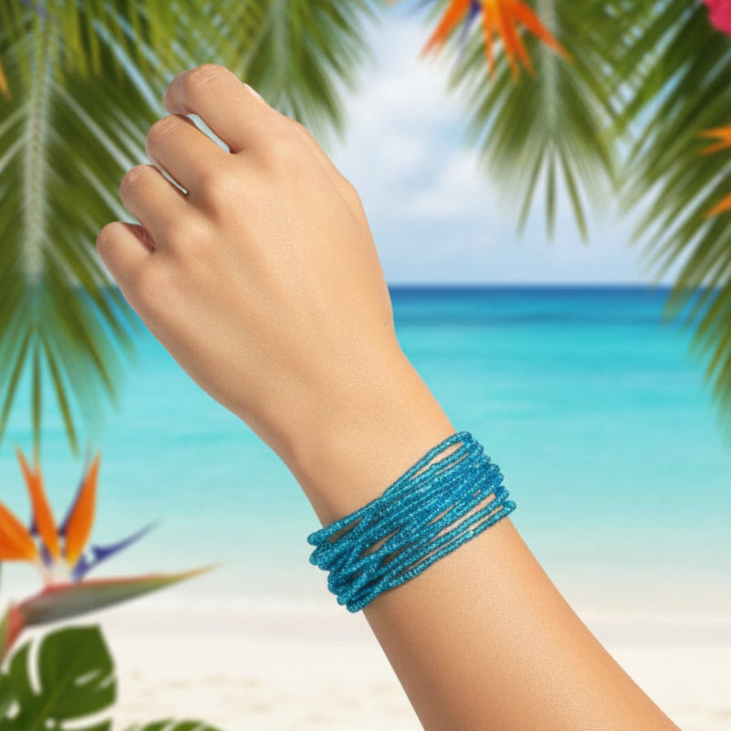 Hand wearing a 1960s Vintage  Mermaid Blue Beaded Bracelet on wrist with a tropical beach background
