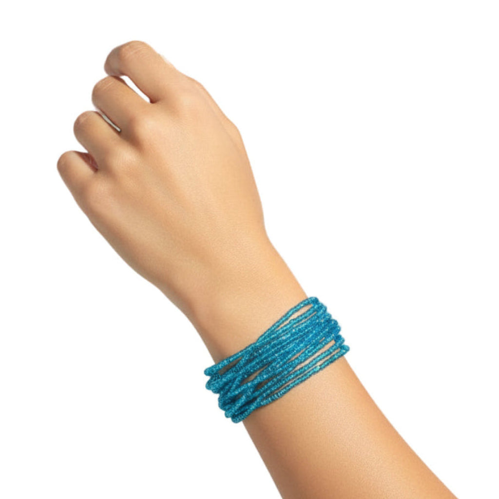 Hand wearing a blue beaded bracelet on a white background
