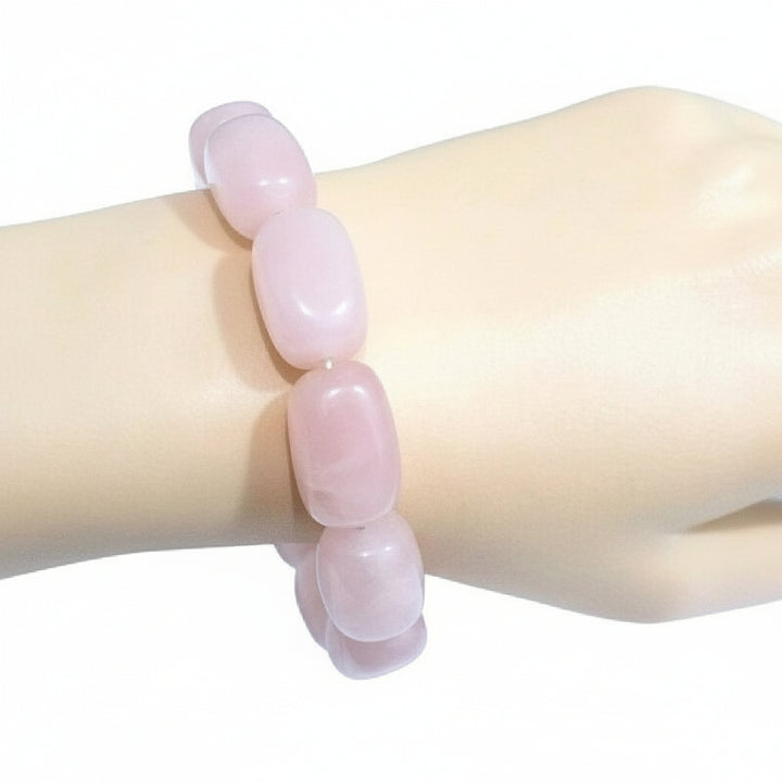 Pink beaded rose quartz bracelet on a mannequin arm with a white background.