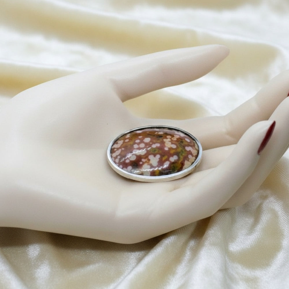 1890 Victorian Ocular Ocean Jasper Oval Cabochon Brooch in a hand for scale.