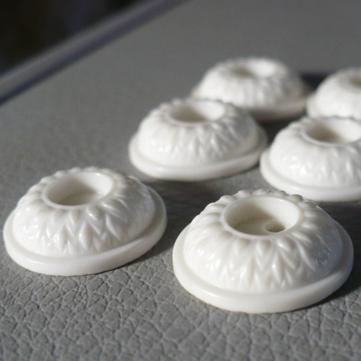 23L Set of Six White Celluloid Whistle Buttons, close-up on gray background.