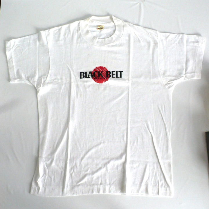 Vintage 1980s white t-shirt with 'Black Belt' logo, front, on a white table top background.