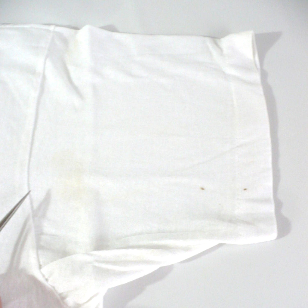 Vintage 1980s white t-shirt with 'Black Belt' logo, enlarged image showing stains at front left sleeve, on a white table top background.