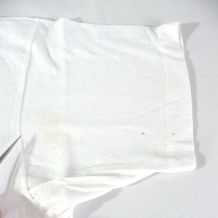 Vintage 1980s white t-shirt with 'Black Belt' logo, enlarged image showing stains at front left sleeve, on a white table top background.