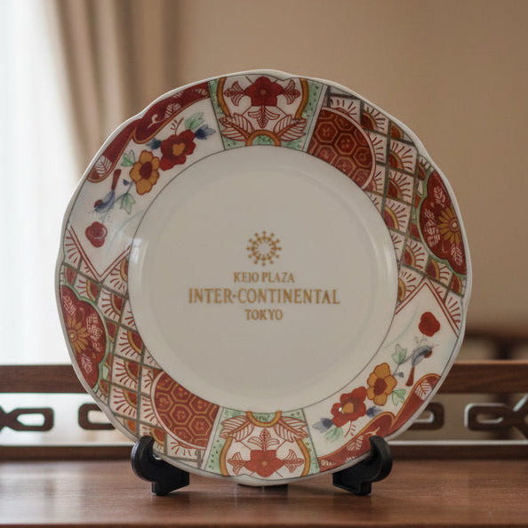 Decorative plate with intricate designs on a wooden stand against a neutral background
