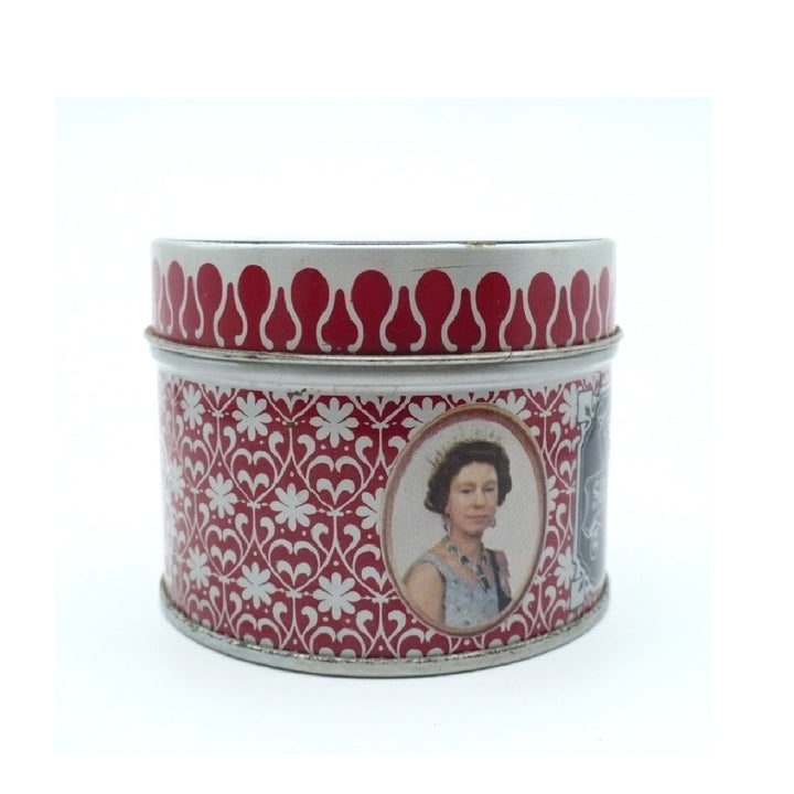 A vintage round metal Matchbox Tin with a red and white floral pattern, featuring an oval portrait of Queen Elizabeth on the front and a red teardrop motif around the rim.