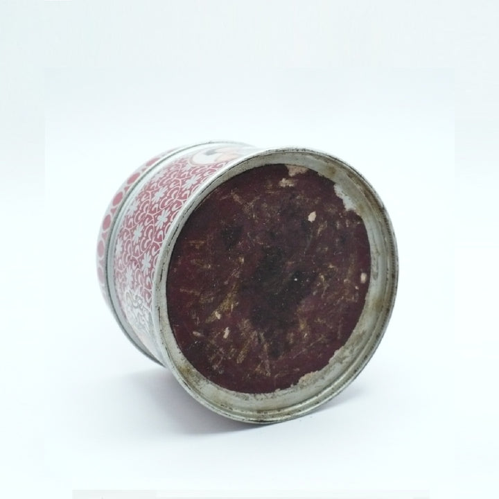 A vintage cylindrical tin Matchbox Tin with a red and white patterned exterior, shown lying on its side on a white background.