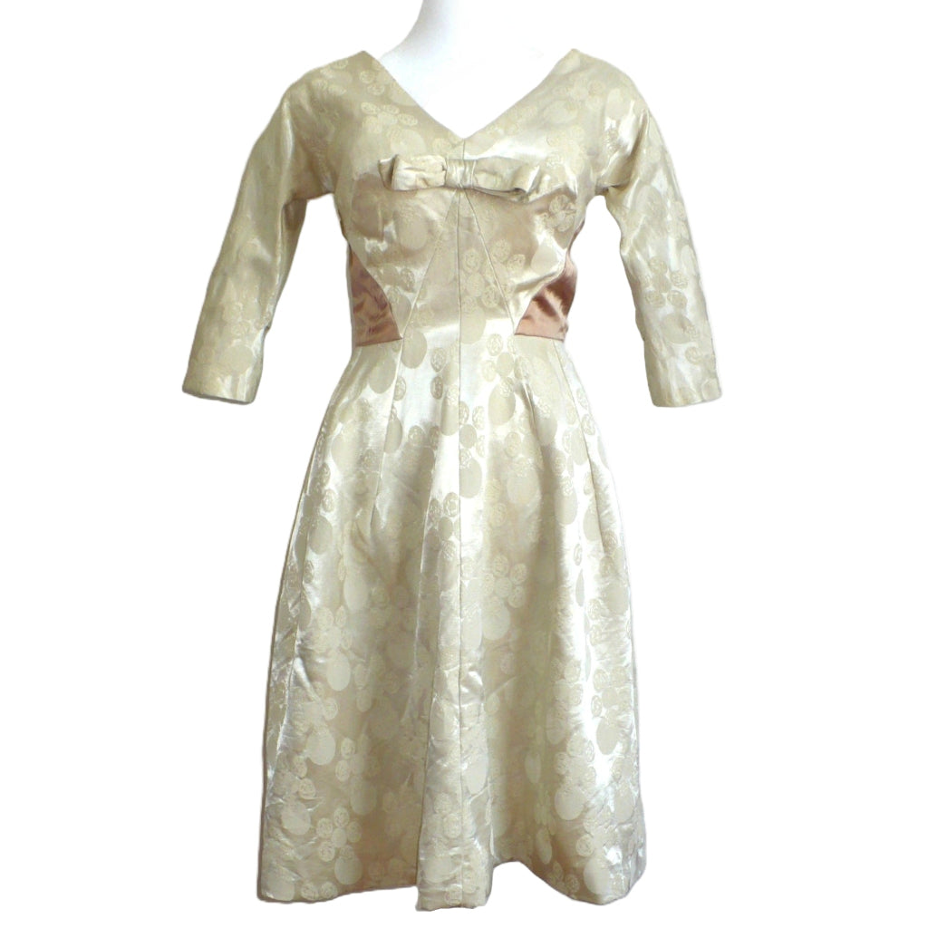 Close-up of the champagne-white jacquard circles pattern and bronze satin waist accent on the 1960s dress.
