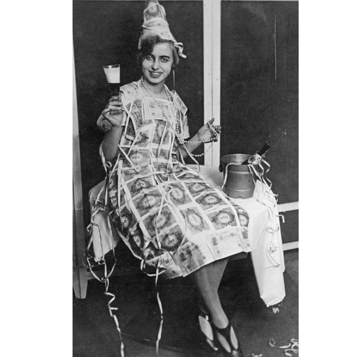 Woman wearing a dress made of hyperinflation German notes sitting on a chair.
