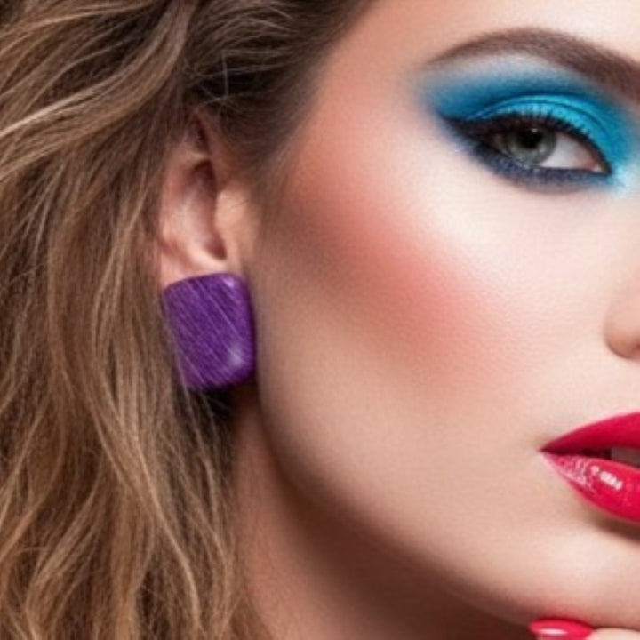 Close-up of a woman's face with colorful makeup and purple earrings.