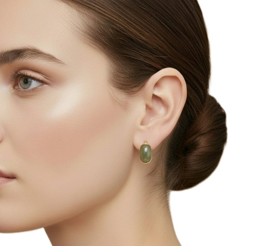 Close-up of a woman wearing a 1970s Vintage Givenchy Designer Hoop Earrings, Signed Gold-tone and Olive Green Clip-on Earrings. on a white background
