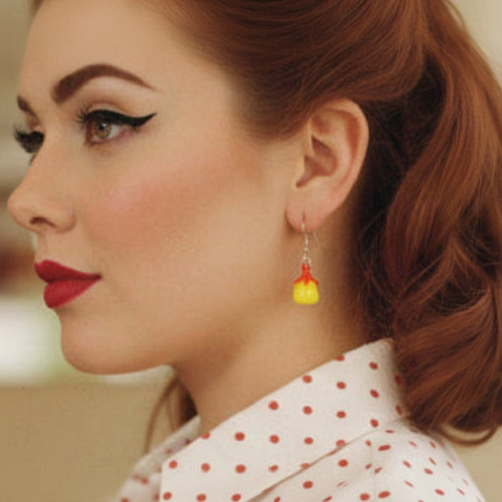 Woman with vintage hairstyle and makeup wearing a polka dot blouse and fruity earrings.
