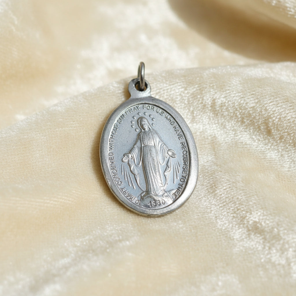 1940s Vintage WWII Eloxal Aluminum Miraculous Medal Pendant on cream velvet background, front view.