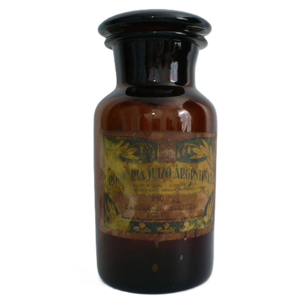 19th-century hand-blown amber glass apothecary jar with a label indicating it once contained cardamon seed powder. The jar has a dark amber color, a narrow neck, and a round stopper.
