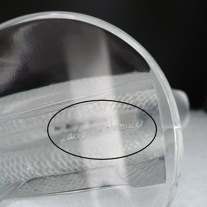 A frosted crystal fish sculpture, Perche Bouchon de Radiateur: Perch Car Mascot, displayed on a clear glass stand against a neutral beige background, base with Lalique  France.