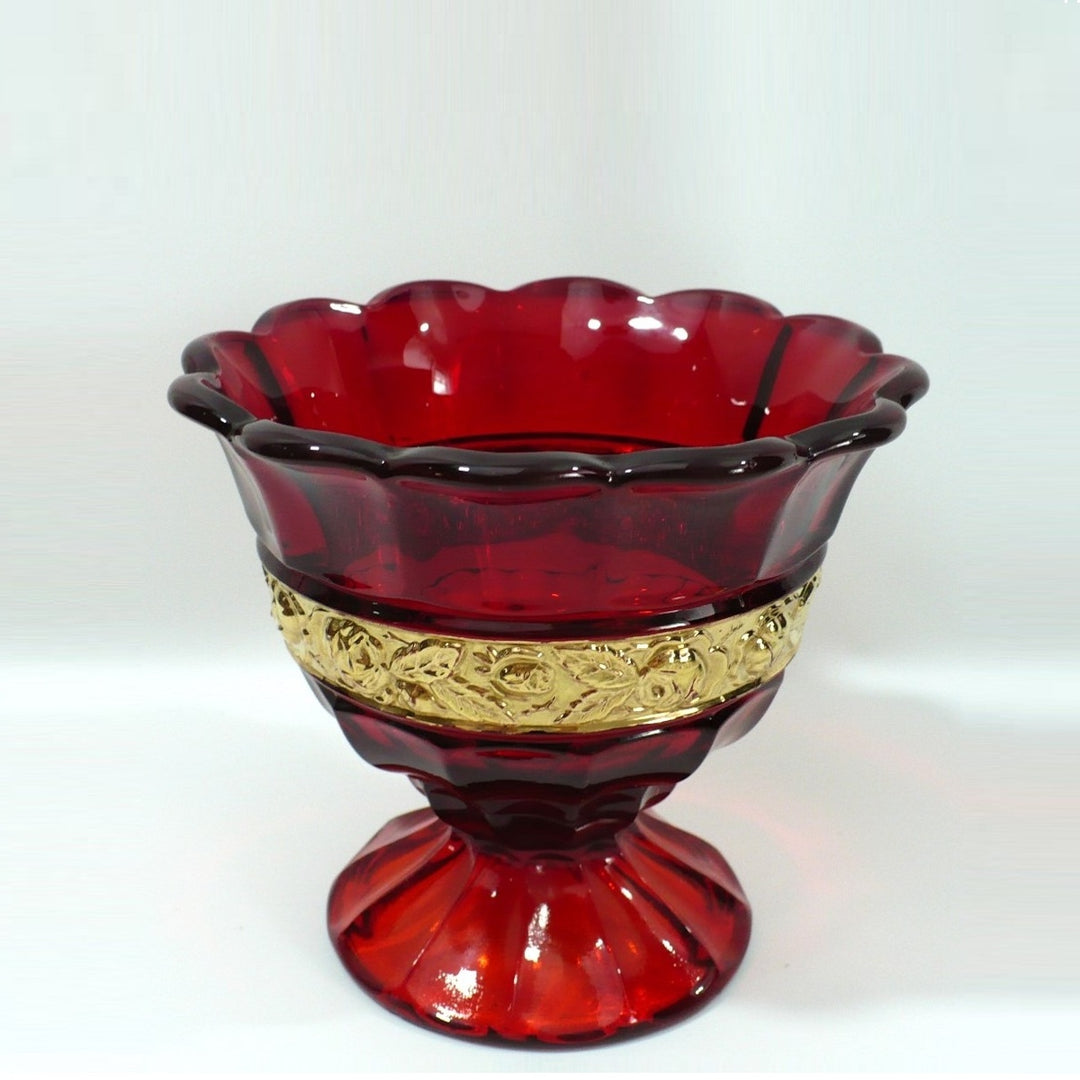 A vintage red glass pedestal bowl with a scalloped rim and a decorative gold band around the middle, set against a plain white background: 1929-1931 Red Ariadne Sugar Basin by Brockwitz.